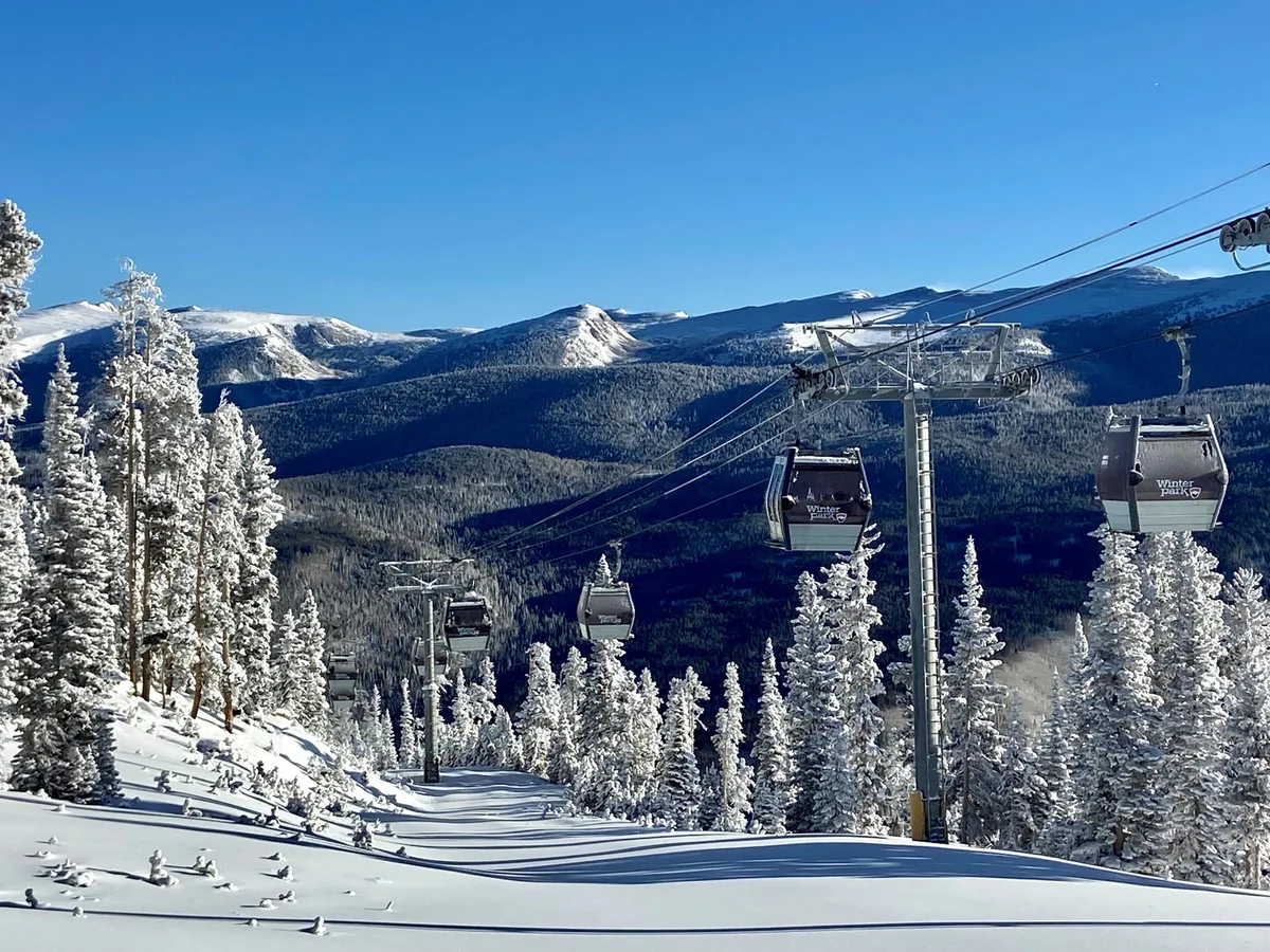 This exterior image captures ski lift gondolas gliding over a snowy, mountainous landscape with snow-covered trees, conveying the thrill of immediate access to world-class skiing and mountain adventures. The breathtaking backdrop sets the tone for year-round outdoor exploration in the area.