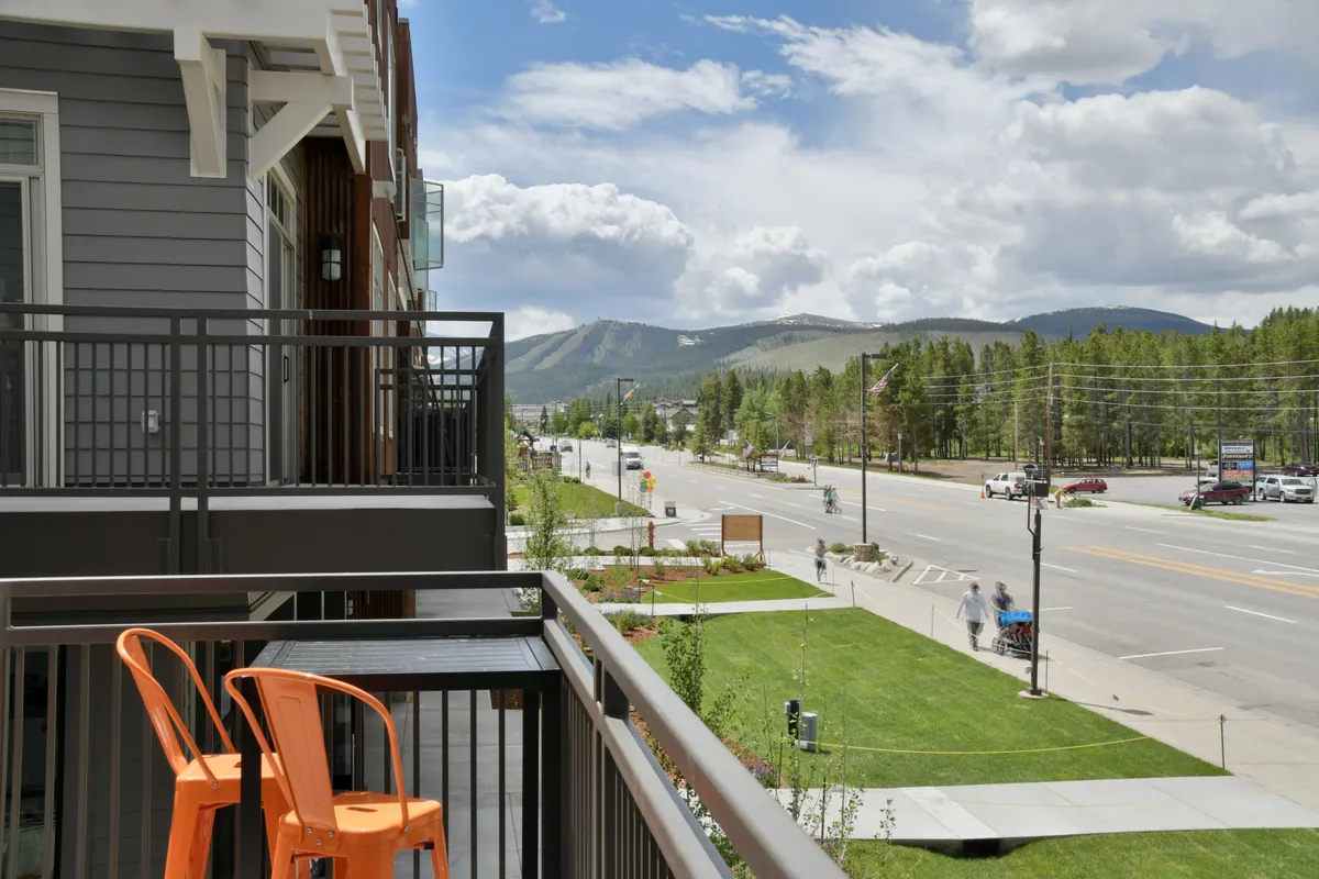 A vibrant view from a balcony with eye-catching orange chairs overlooking sweeping mountain vistas and a lively street scene. The setting invites relaxation, socializing, and soaking in panoramic views—perfect for swapping adventure stories at sunset or enjoying the landscape year-round.