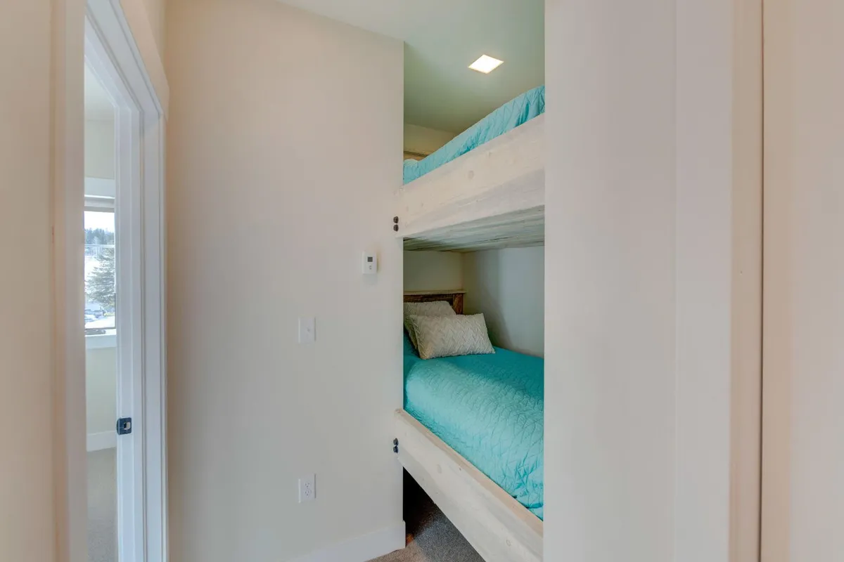 A playful and cozy bedroom with bunk beds, soft textured bedding, and abundant natural light streaming through a window. The space invites both relaxation and family bonding.